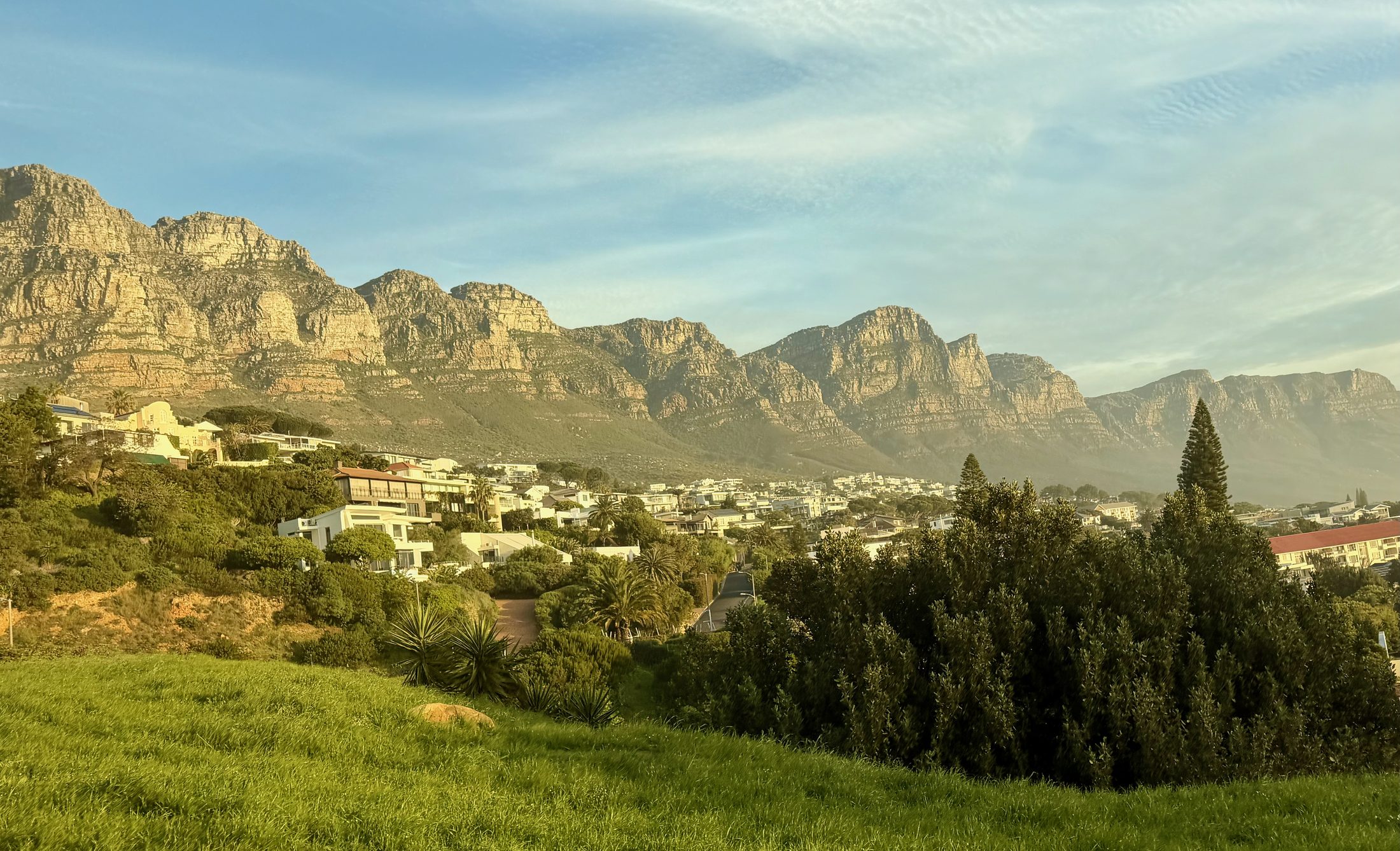 A bay below a long ridge of mountains, town spread along the shore in late light