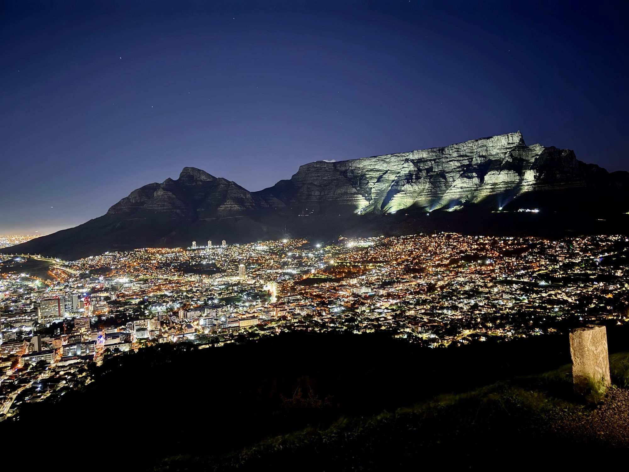 Table Mountain lit at night above the glittering lights of the city