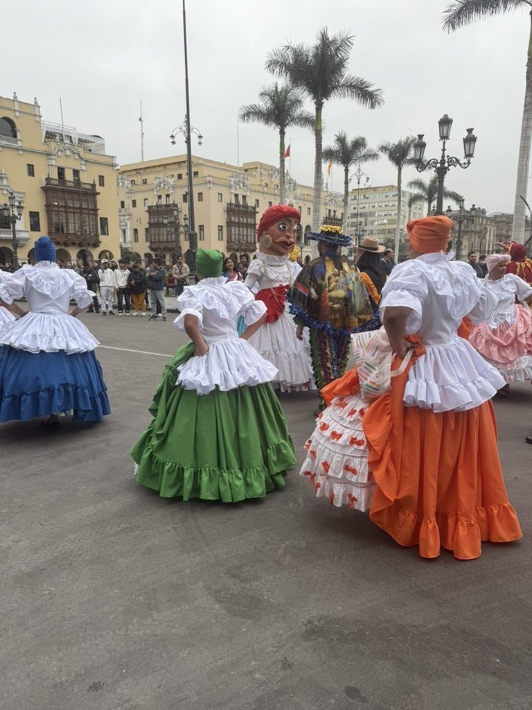 Dancers in full skirts of green, orange and blue performing in a colonial plaza in Lima