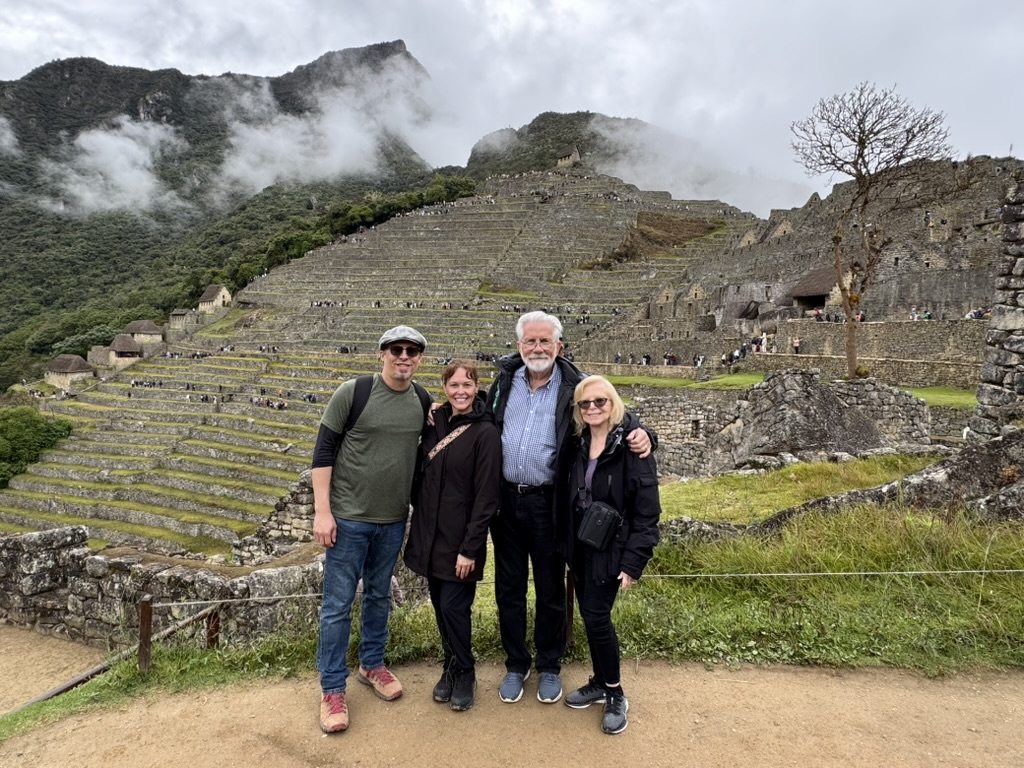 Four travellers standing above the terraces of Machu Picchu with the cloud lifted