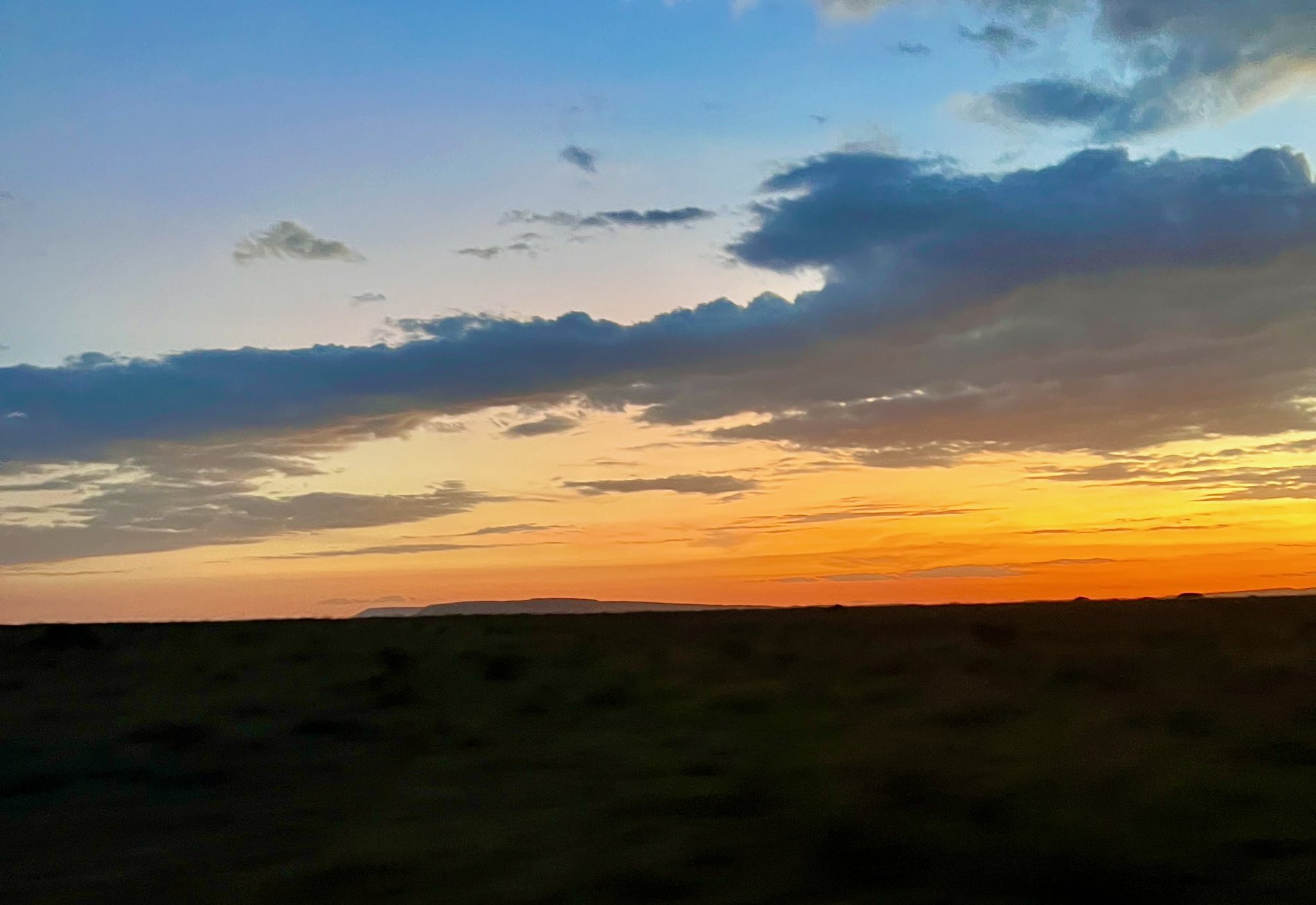 Sunset over the plain, banded cloud above a dark horizon