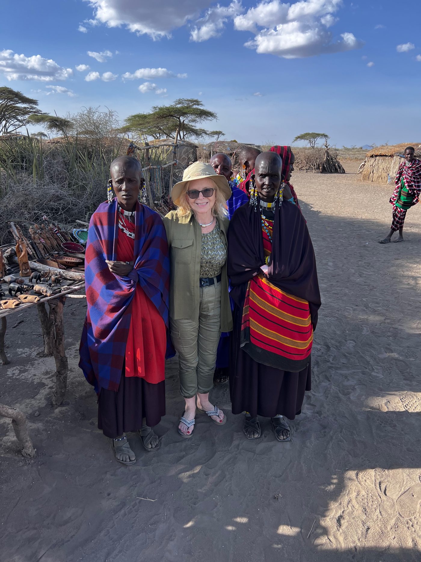 Dana Wallace Cash standing with two Maasai women in beaded dress at the visitor village